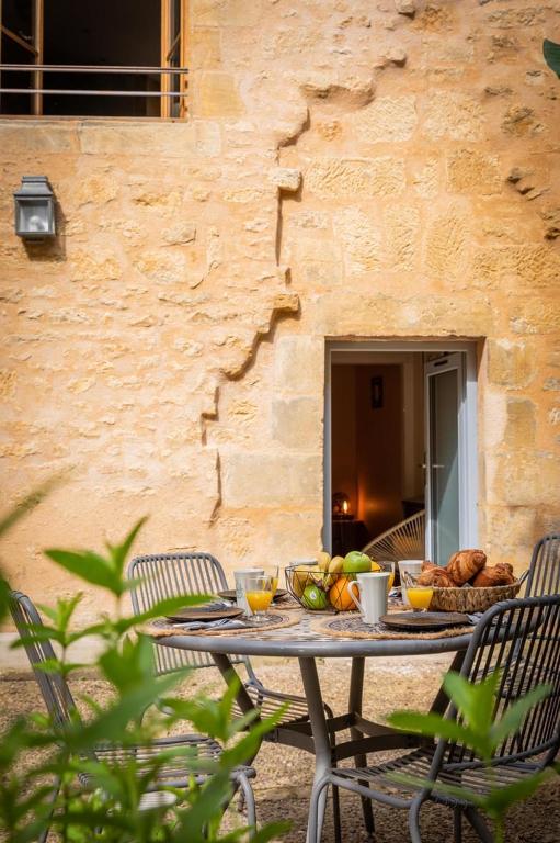 une table avec des fruits devant un bâtiment dans l'établissement Le jardin de la Paix - Centre historique, à Sarlat-la-Canéda
