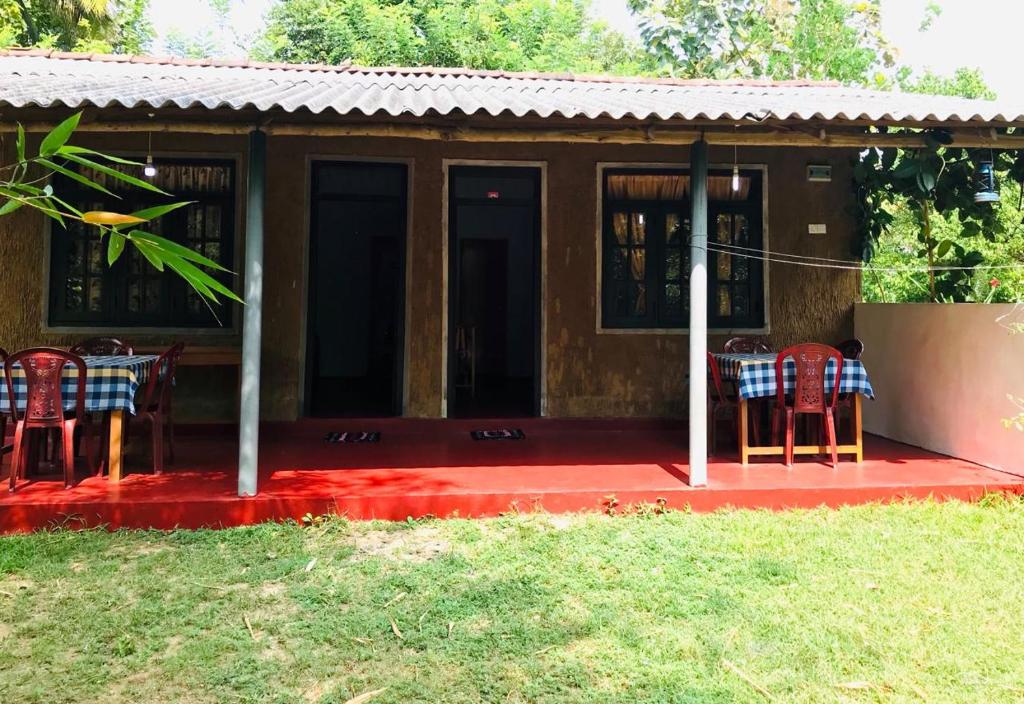 Una pequeña casa con sillas y una mesa sobre una alfombra roja. en Gami Gedara Homestay, en Polonnaruwa