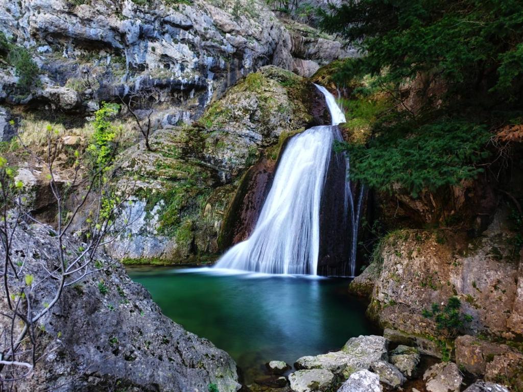 a waterfall in a canyon with a body of water at Casa Rural la Piedra del Cambrón in Villaverde de Guadalimar