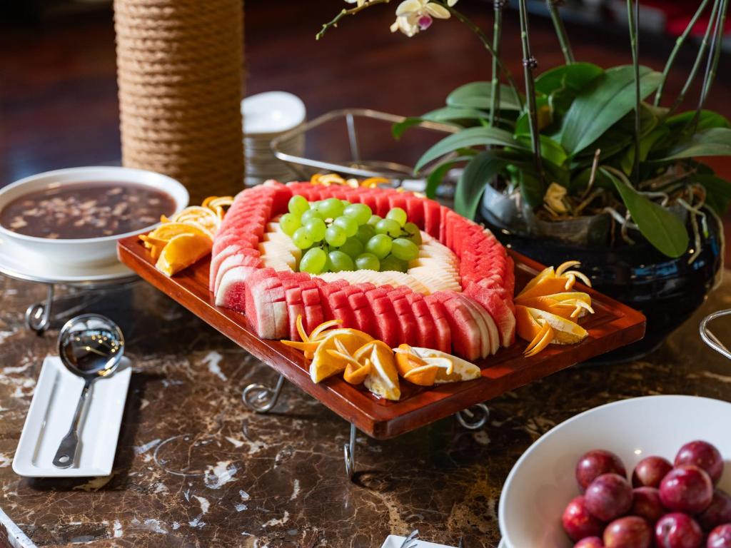 a plate of food with grapes on a table at Amanda Luxury Cruise in Ha Long