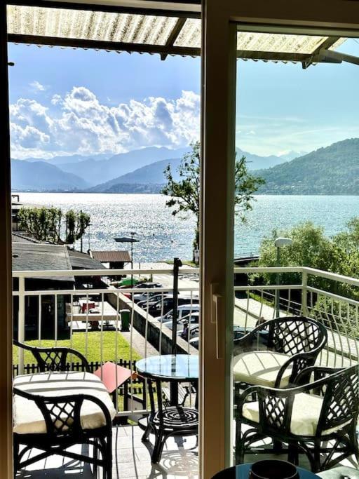 a balcony with tables and chairs and a view of the water at Lilly del Lago Maggiore in Castelveccana