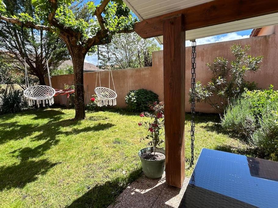 une arrière-cour avec deux balançoires et un arbre dans l'établissement Maison cosy proche du lac, à Lacanau