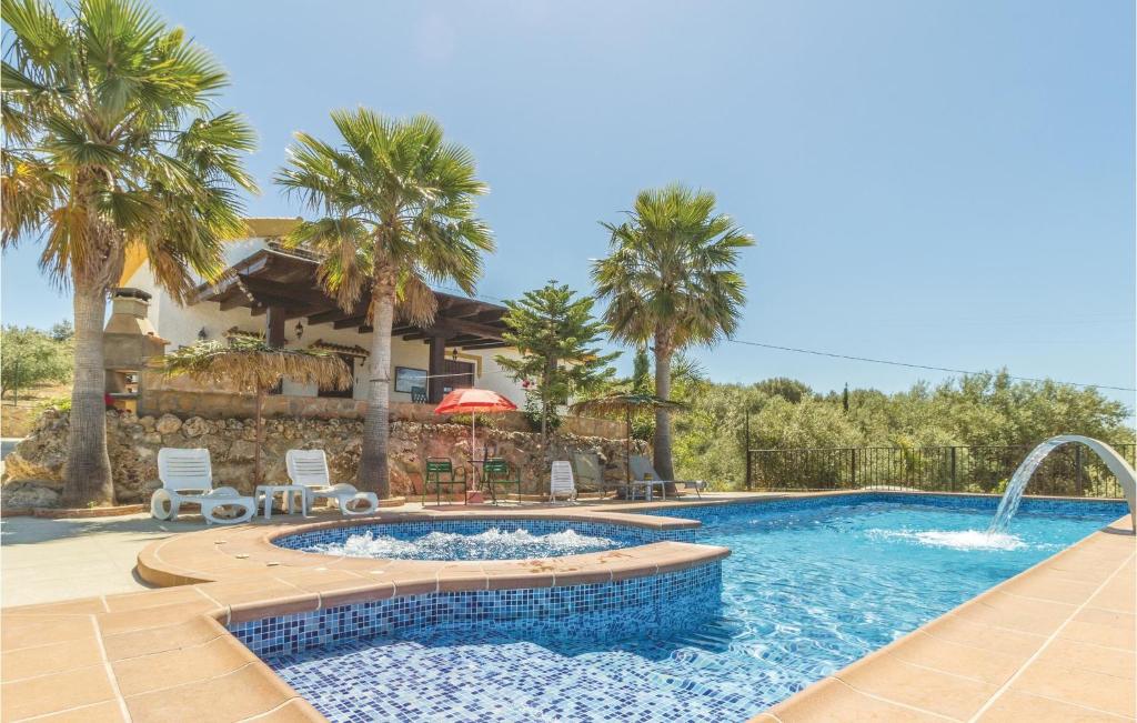 a swimming pool in front of a house with palm trees at Pet Friendly Home In Periana in Los Baños de Vilo