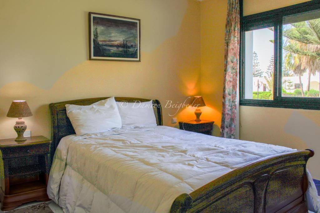 a bedroom with a large bed and a window at Charmant appartement au bord de mer in El Jadida