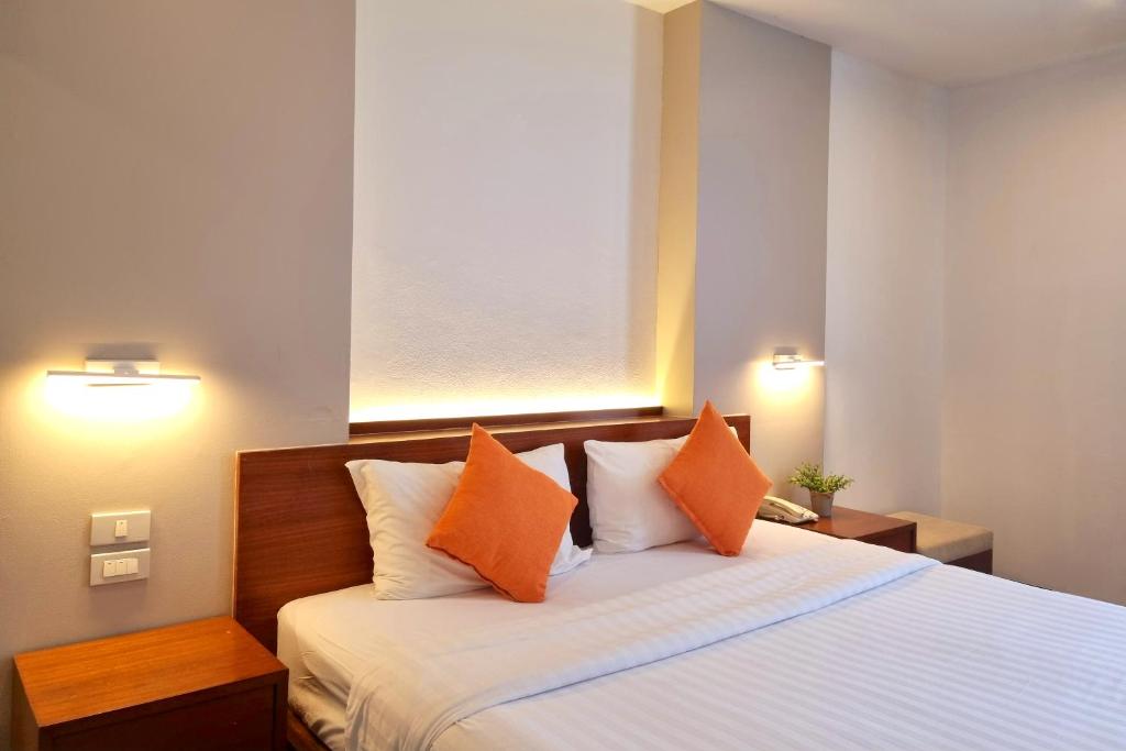 a bedroom with a large bed with orange pillows at Lantana Resort Hotel Bangkok in Bangkok