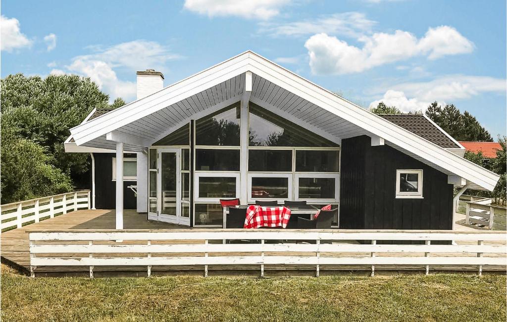 a black house with a deck with a table at Beautiful Home In Nakskov With Sauna in Nakskov