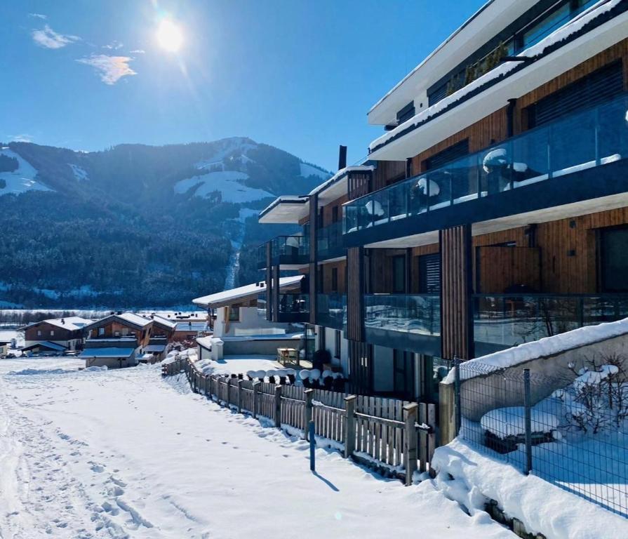 een gebouw in de sneeuw met bergen op de achtergrond bij Apartment EMILY Brixental in Brixen im Thale