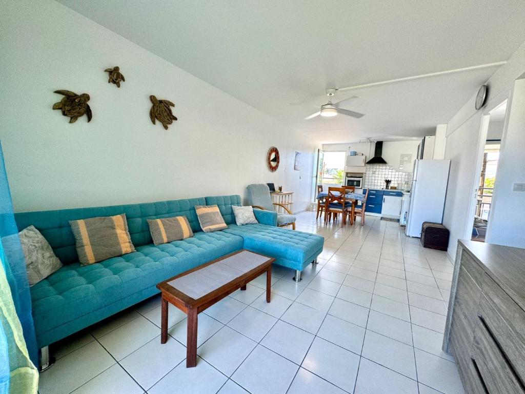 a living room with a blue couch and a kitchen at Grand appartement confortable 2 chambres proche marina in Saint-François