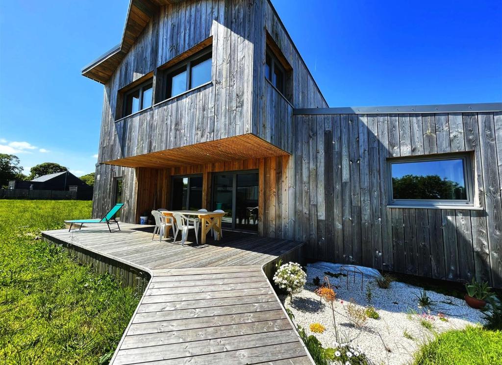 une maison en bois avec une table et des chaises sur une terrasse dans l'établissement maison Porzh Loaz., à Plouézec