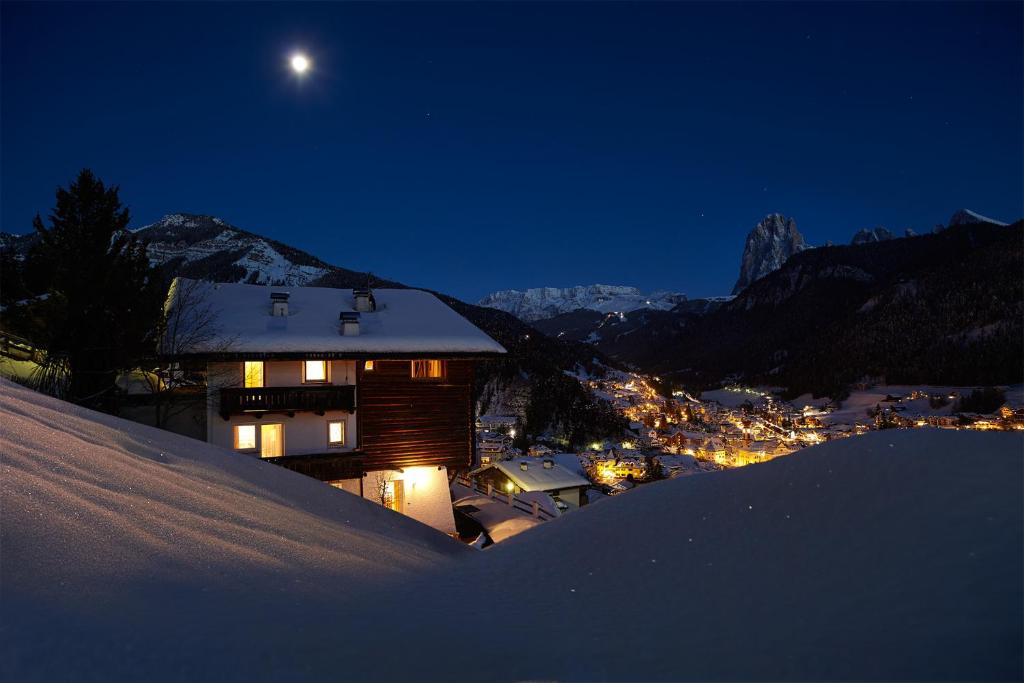 a house in the snow at night with the moon at Cësa Marmolada 1318 in Ortisei