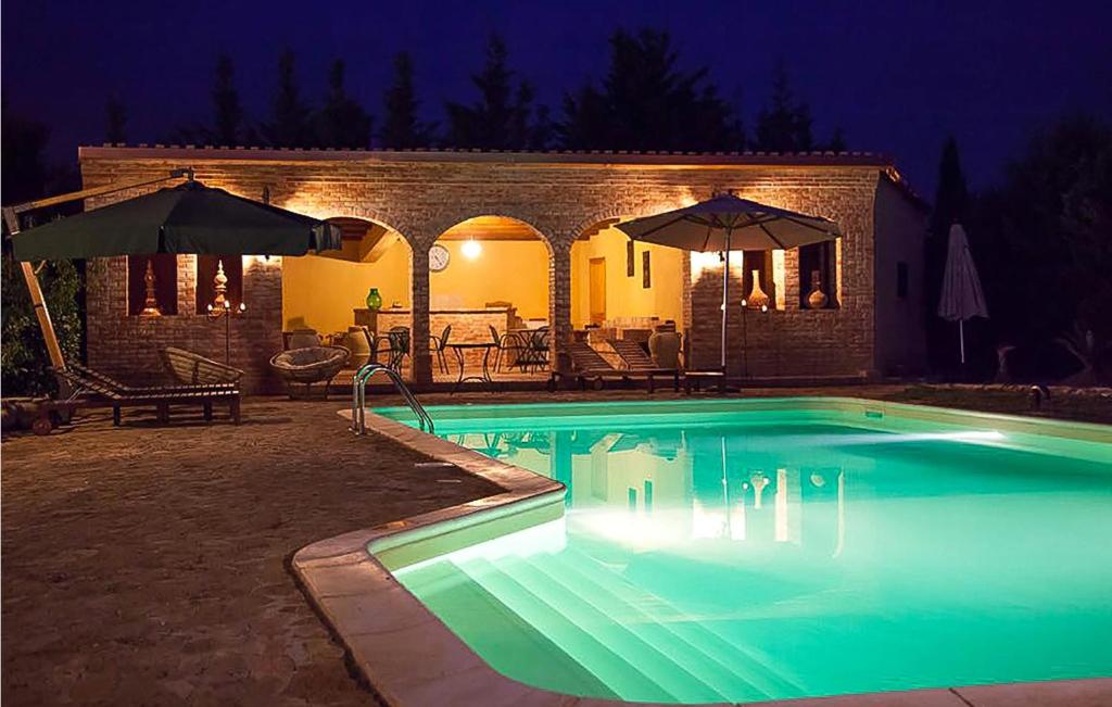 a swimming pool at night with umbrellas at Amazing Home In Chiaramonte Gulfi in Chiaramonte Gulfi