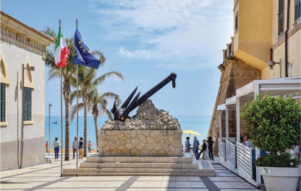 a statue on a street next to the ocean at Amazing Home In Chiaramonte Gulfi in Chiaramonte Gulfi