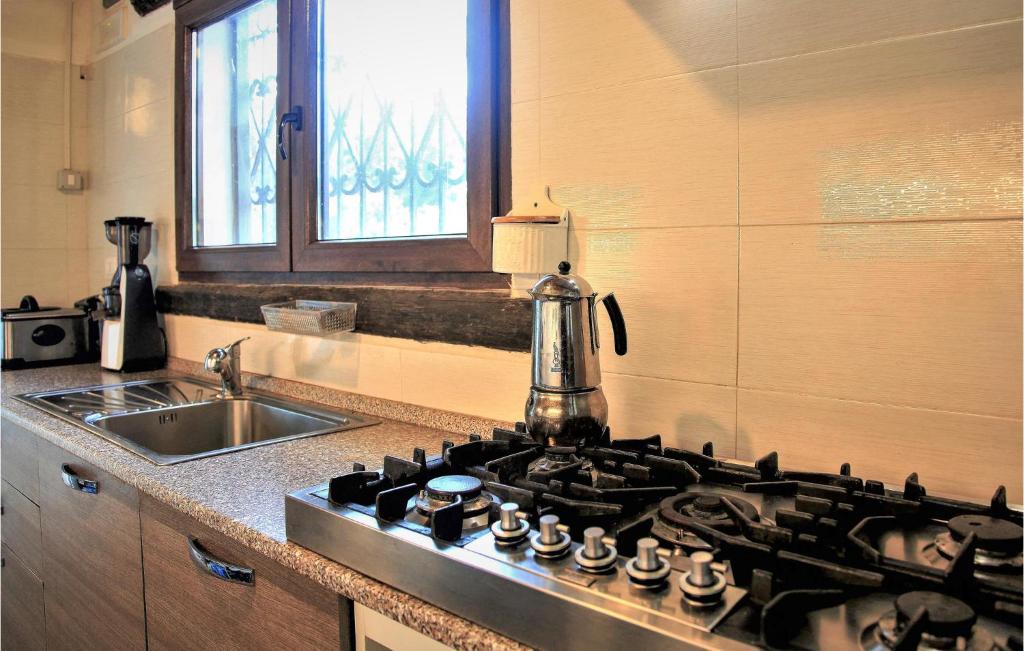 a kitchen with a stove top oven and a sink at Amazing Home In Chiaramonte Gulfi in Chiaramonte Gulfi