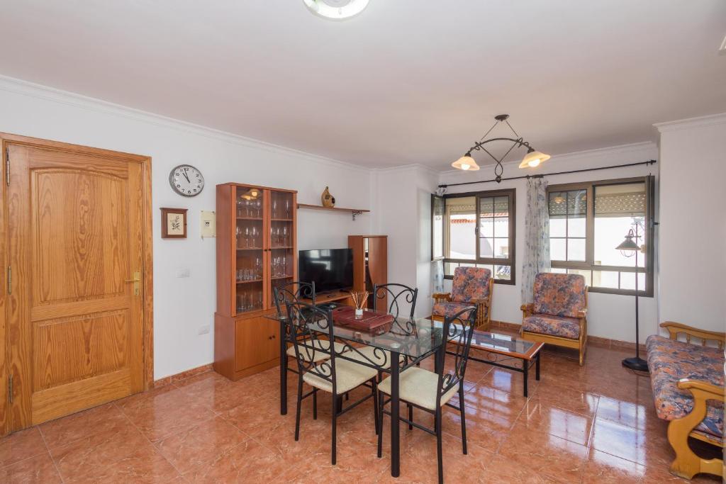 Una sala de estar con una mesa y sillas y un televisor. en Playa Arinaga junto al mar, en Agüimes