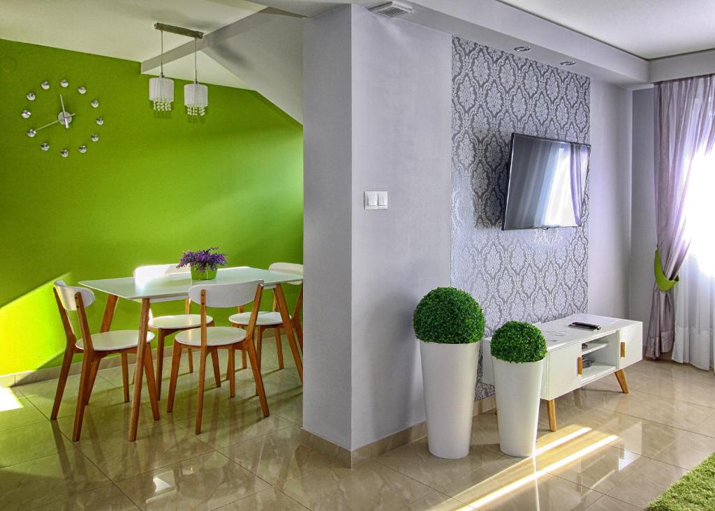 uma sala de jantar com paredes verdes e uma mesa e cadeiras em Apartament Lux em Krościenko