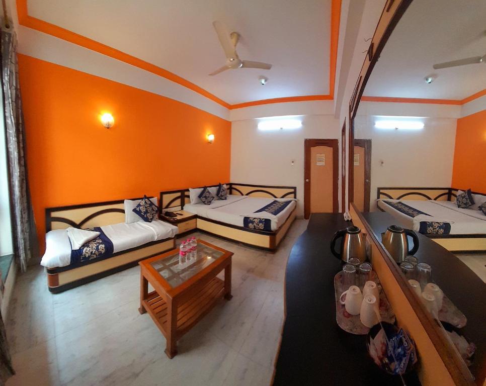 a room with three beds and a table at Hotel Indore Palace - Newly Renovated Hotel in Shirdi