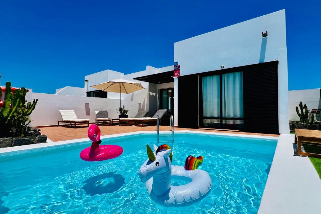 Una piscina con un flotador de unicornio frente a una casa. en El Salto 37 - Rinnovata 2023, Piscina Riscaldata, Sole tutto il giorno! Wi-Fi, Massima privacy, Ottima posizione, en Playa Blanca