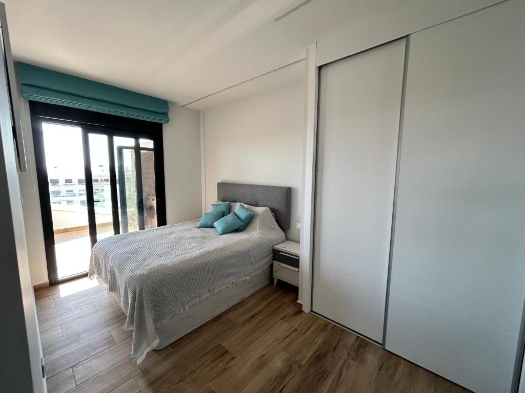 a bedroom with a bed with blue pillows on it at SPANISH SUN - 500 m from the beach in Arenales del Sol