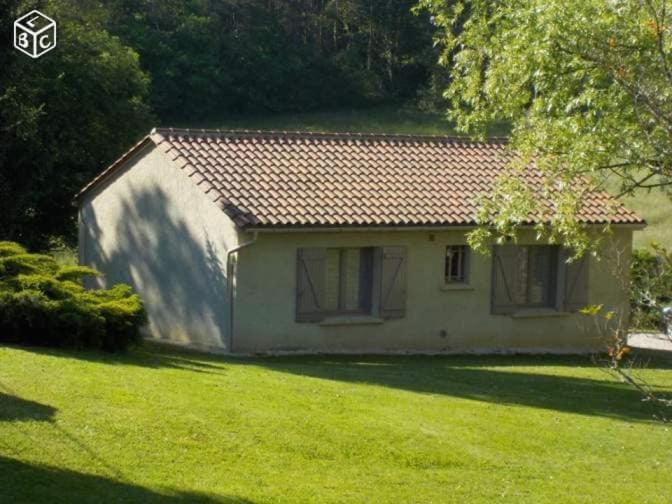 una pequeña casa en un patio con césped verde en Gîte Bégonia dans un cadre idyllique, idéalement situé, en Castels