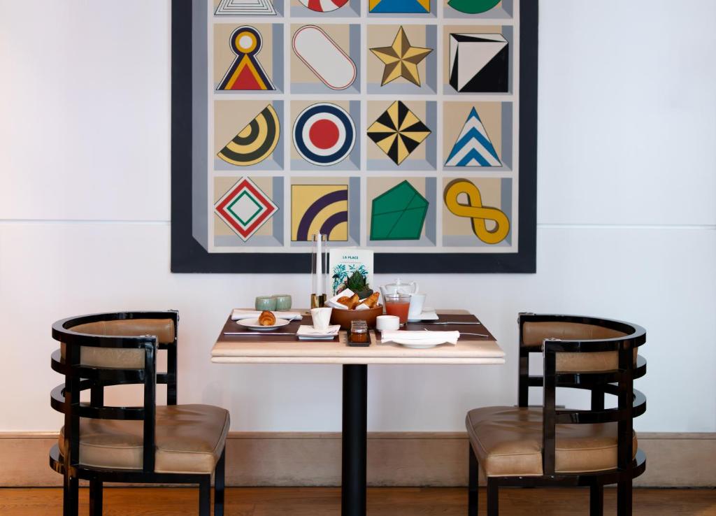 a table with two chairs and a picture on the wall at Grand Hôtel Champs-Elysées in Paris