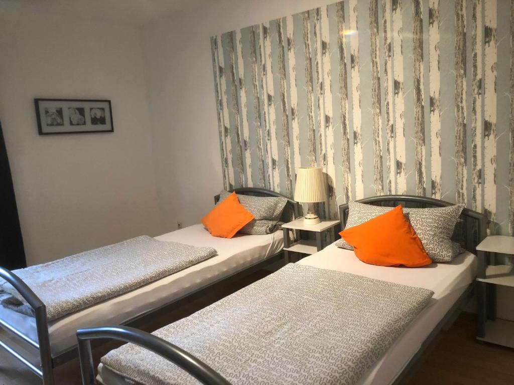 two beds with orange pillows in a room at Monteurwohnung in Salzgitter