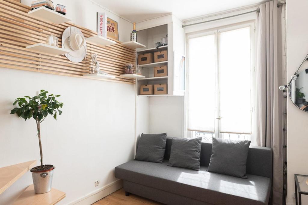 un salon avec un canapé et une fenêtre dans l'établissement Cosy Apartment In Paris, à Paris