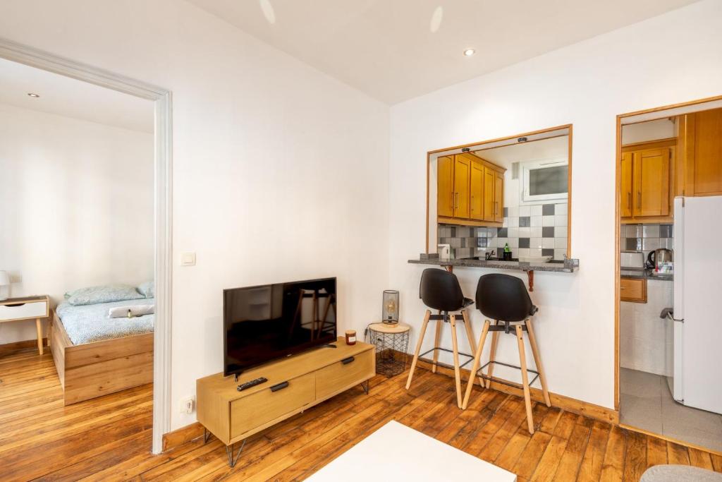 un salon avec une télévision et deux tabourets dans l'établissement GuestReady - Cozy Apt 10 mins from Arc de Triomphe, à Paris