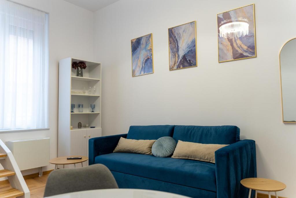 a blue couch in a living room with paintings on the wall at Poema in Oradea