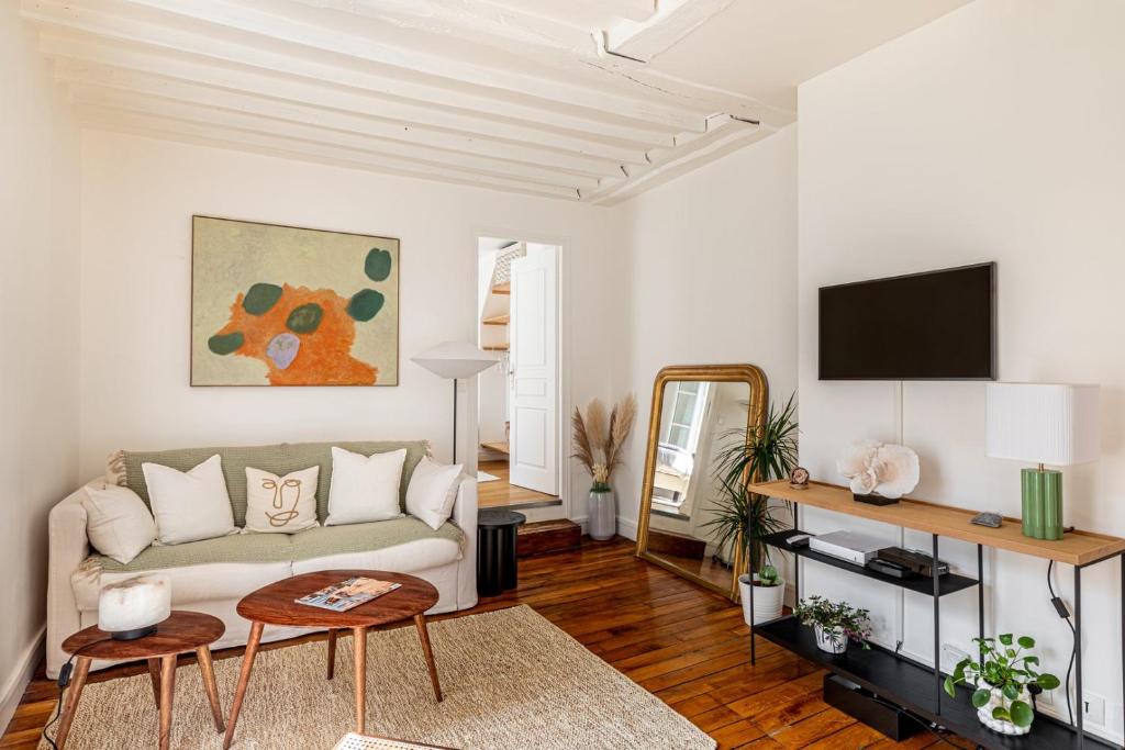 un salon avec un canapé et une télévision dans l'établissement GuestReady - Apt de charme dans le centre de Paris IX, à Paris