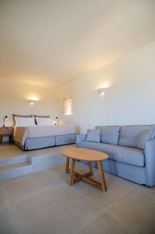 a bedroom with a bed and a couch and a table at Alma Sunset Suites in Ios Chora