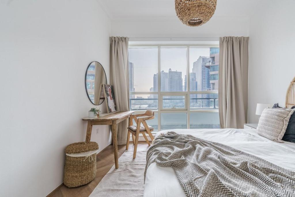 a bedroom with a bed and a desk and a window at GuestReady - Bohemian Apt with Marina View in Dubai