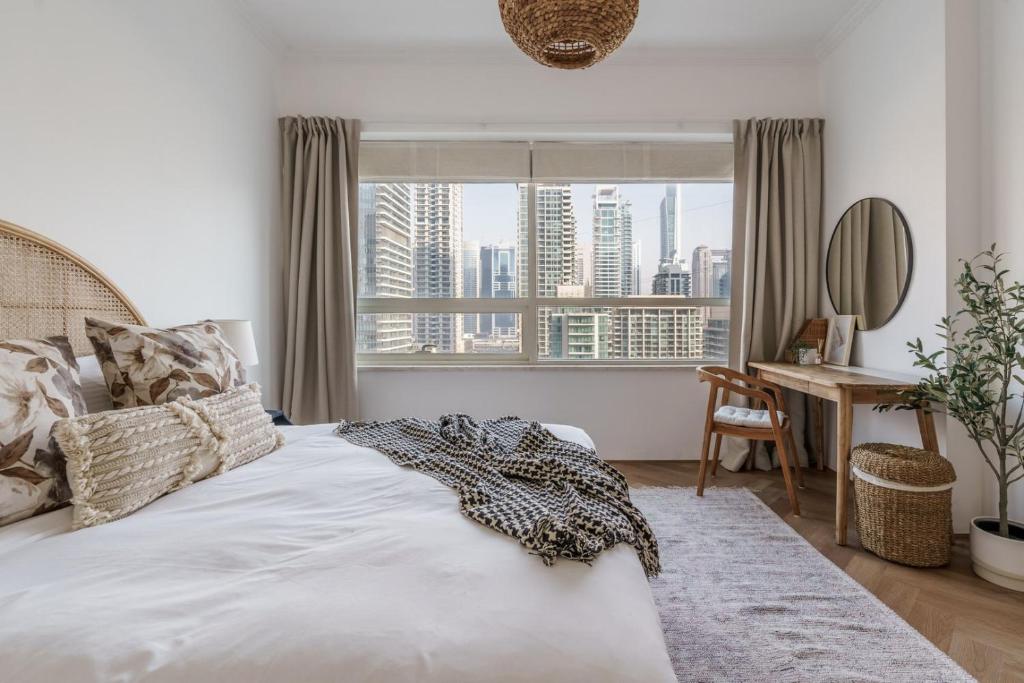 a bedroom with a bed and a desk and a window at GuestReady - Bohemian Apt with Marina View in Dubai