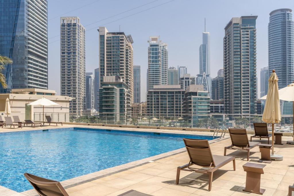 a swimming pool with chairs and a city skyline at GuestReady - Bohemian Apt with Marina View in Dubai