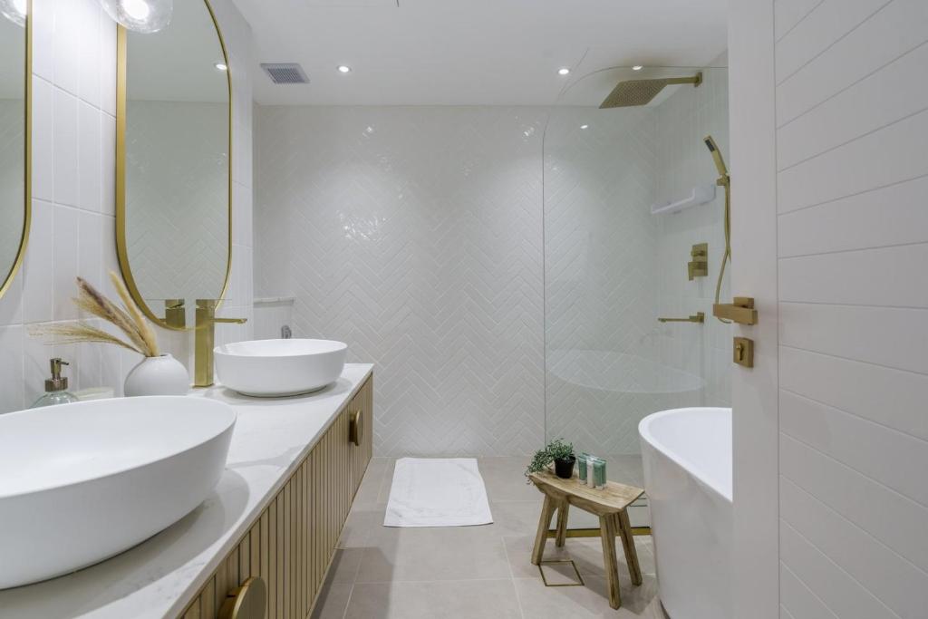 a white bathroom with two sinks and a shower at GuestReady - Bohemian Apt with Marina View in Dubai