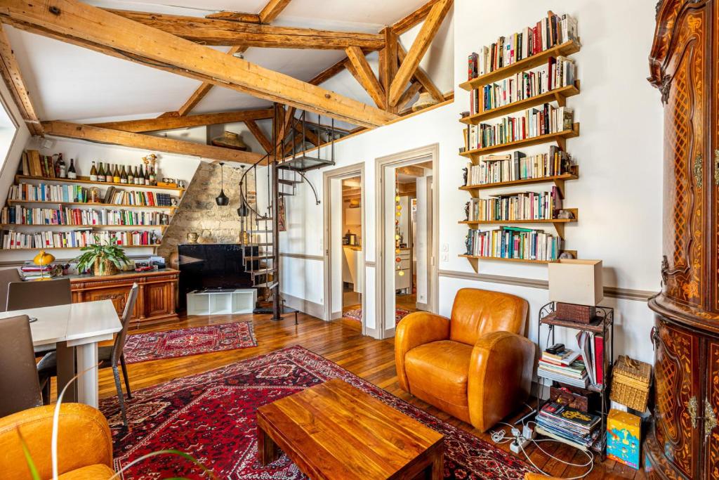 Elle comprend un salon doté de plafonds en bois et d'étagères. dans l'établissement GuestReady - Charming apartment with mezzanine, à Paris
