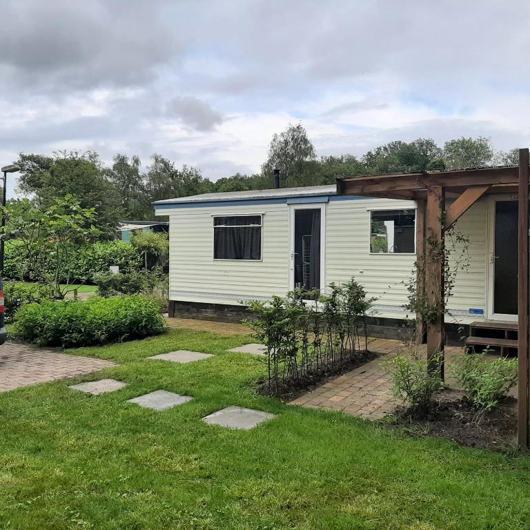 a small white house in a garden at Stacaravan in De Pol