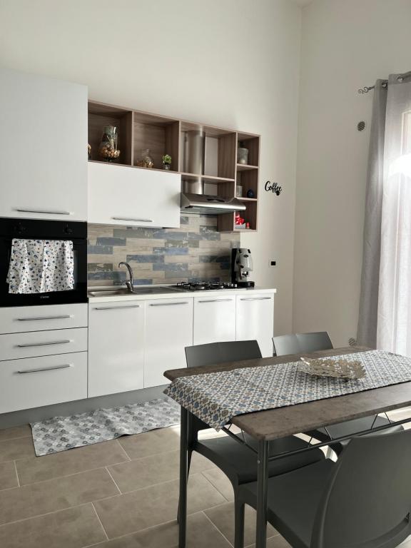 a kitchen with white cabinets and a table and chairs at Azzurra in Terrasini
