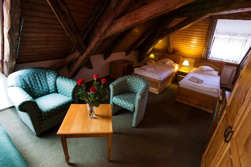 een zolderkamer met 2 bedden en een tafel met bloemen bij Hotel U Lípy in Krušovice