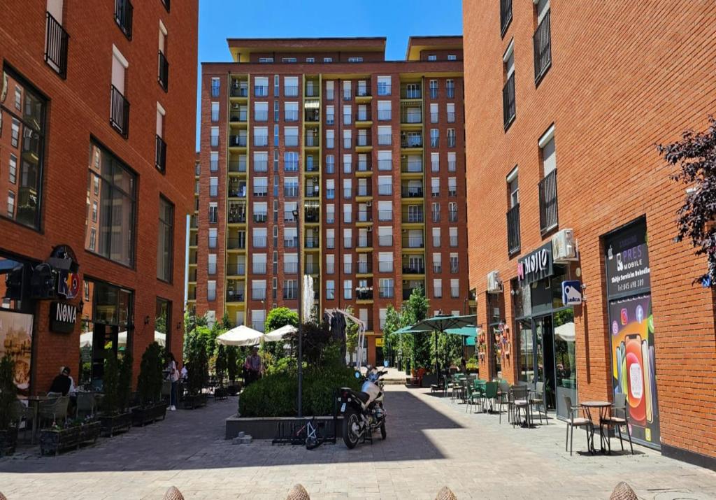 a city street with buildings and tables and a person on a bike at Superb 1 bedroom in the best zone of the city. in Ferizaj