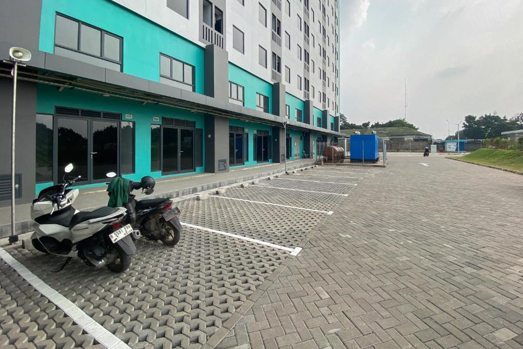 une moto garée sur un parking à côté d'un bâtiment dans l'établissement Apartment Riverdale by Dani room, à Tanahbaru