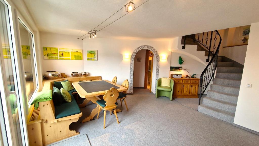 Una habitación con una mesa y sillas y una escalera. en Chesa Bellaval, Haus Leivra 6½-Zimmerwohnung, en Silvaplana