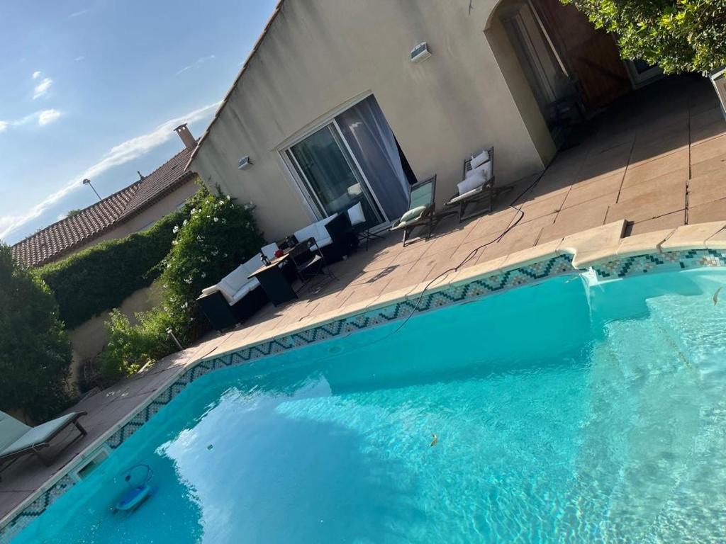 une grande piscine bleue à côté d'une maison dans l'établissement VILLA Méditerranéenne calme, PISCINE sans vis à vis, à Boujan-sur-Libron