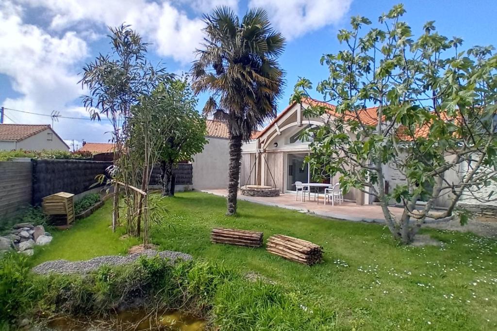 une maison avec un palmier dans une cour dans l'établissement La Bananeraie La Bernerie en Retz, à La Bernerie-en-Retz