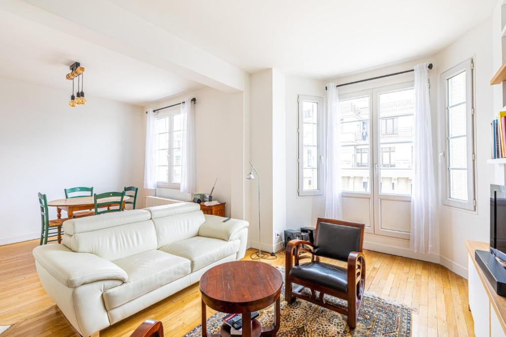 un salon avec un canapé blanc et des chaises dans l'établissement GuestReady - Homely near Montparnasse Tower, à Paris