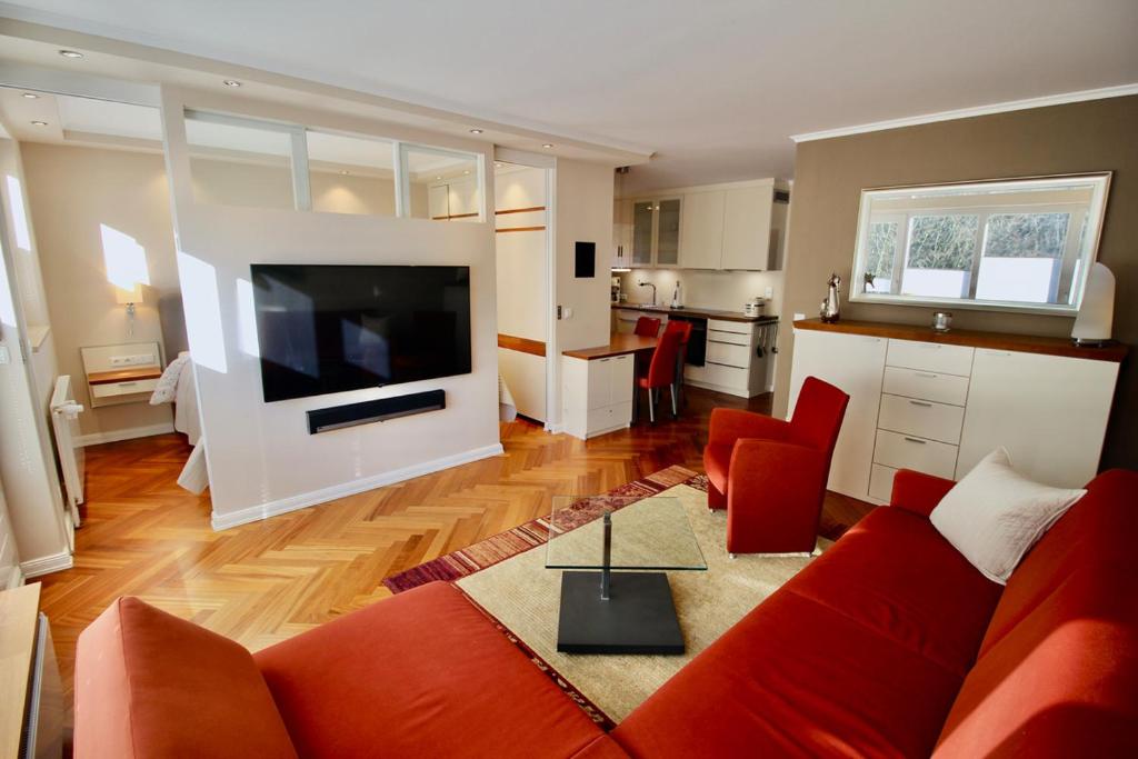 a living room with a red couch and a kitchen at Seepferdchen Suite in Timmendorfer Strand