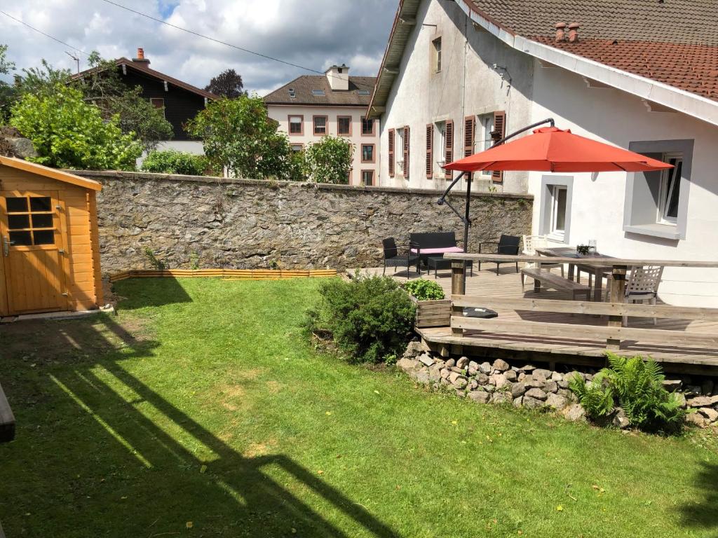 un patio avec une table et un parasol dans une cour dans l'établissement Le Petit Eterlou, à Gérardmer