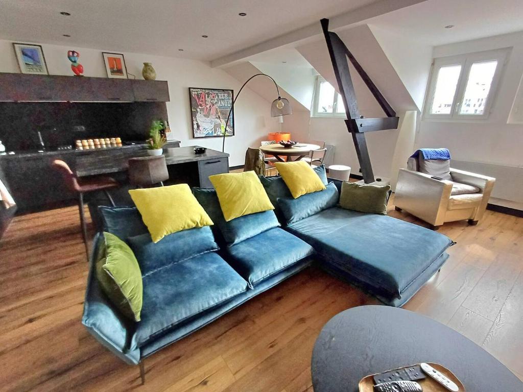 un salon avec un canapé bleu avec des coussins jaunes dans l'établissement Le Hermès, à Lorient