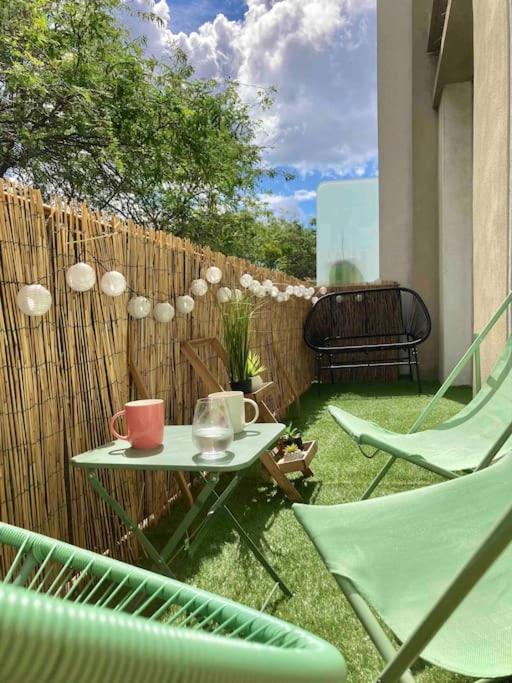 un patio avec une table et des chaises et une clôture dans l'établissement Coeur de ville, balcon & parking gratuit, à Saint-Nazaire