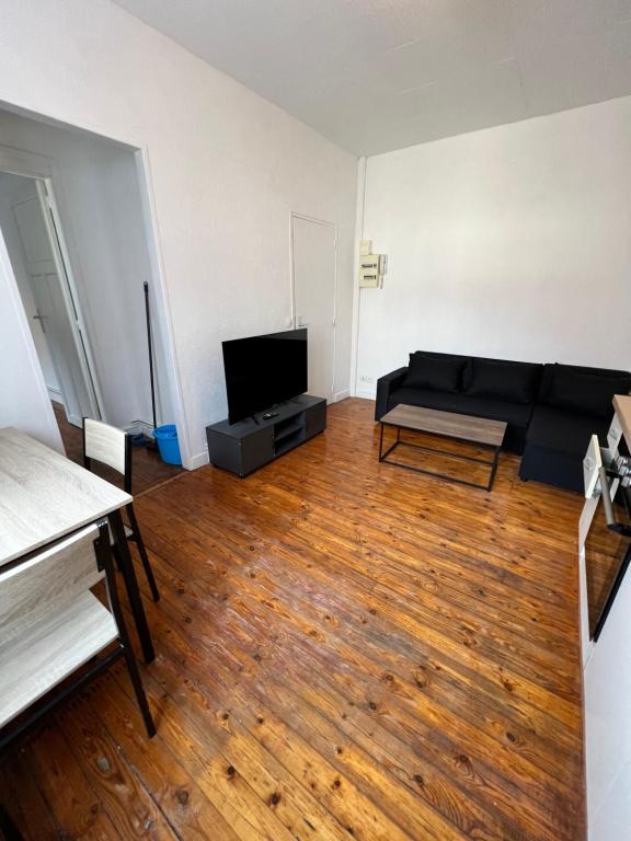 - un salon avec un canapé noir et du parquet dans l'établissement Appt 2 pcs st Quentin Centre, à Saint-Quentin