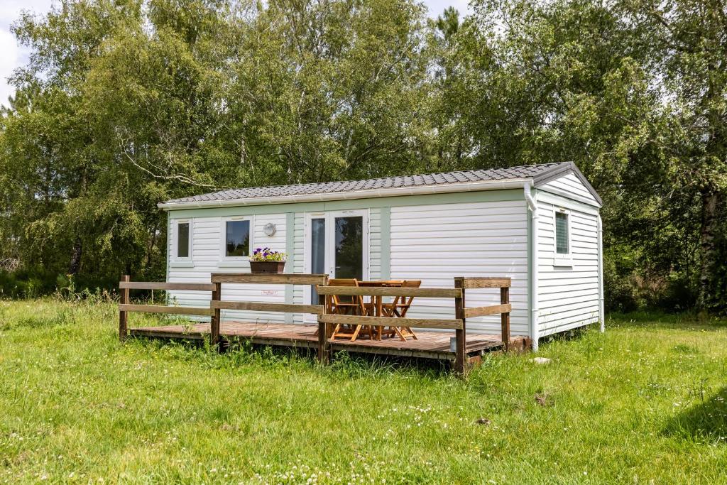 a white shed with a deck in a field at L'héberge du lac d'Isachris mh4 in Queyrac